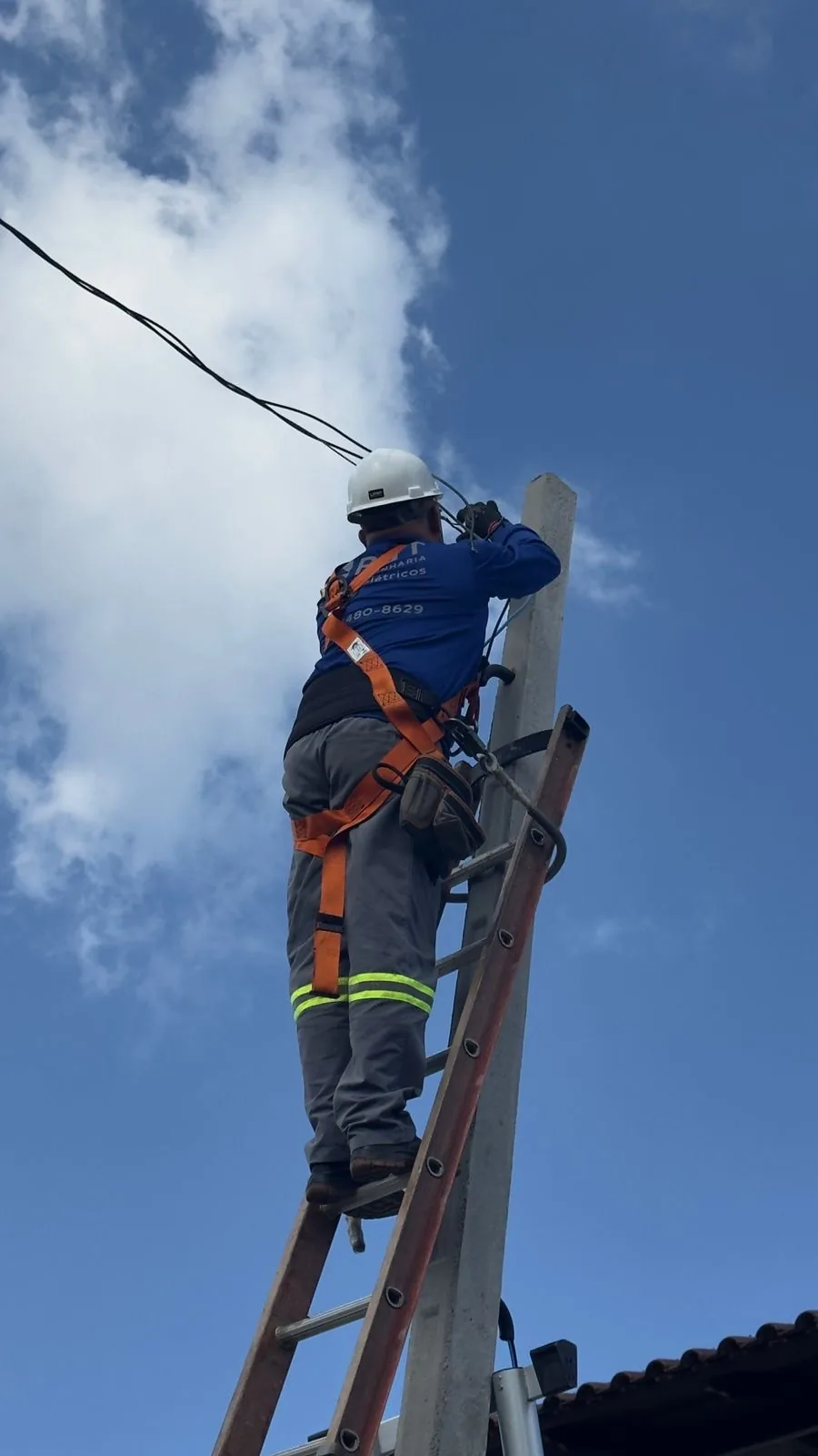 Técnico da RBT Engenharia com equipamento de proteção individual em instalação em poste